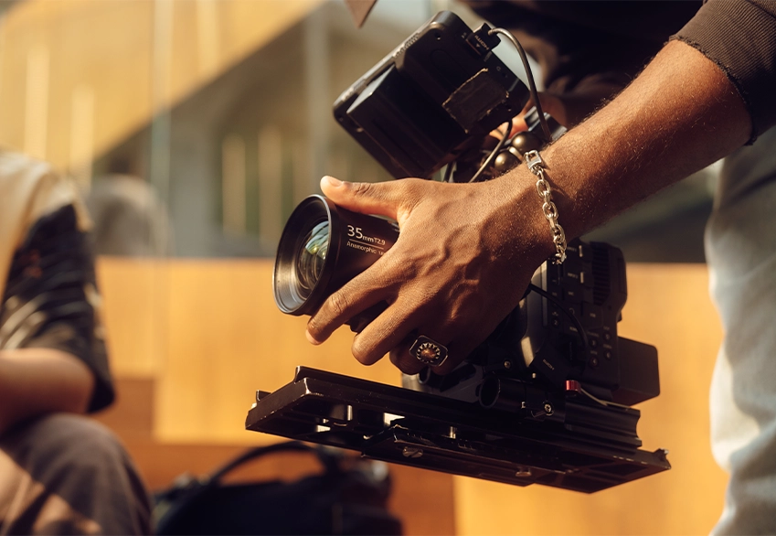 Filmmaker holding a professional cinema camera with a 35mm lens, preparing for a video shoot.